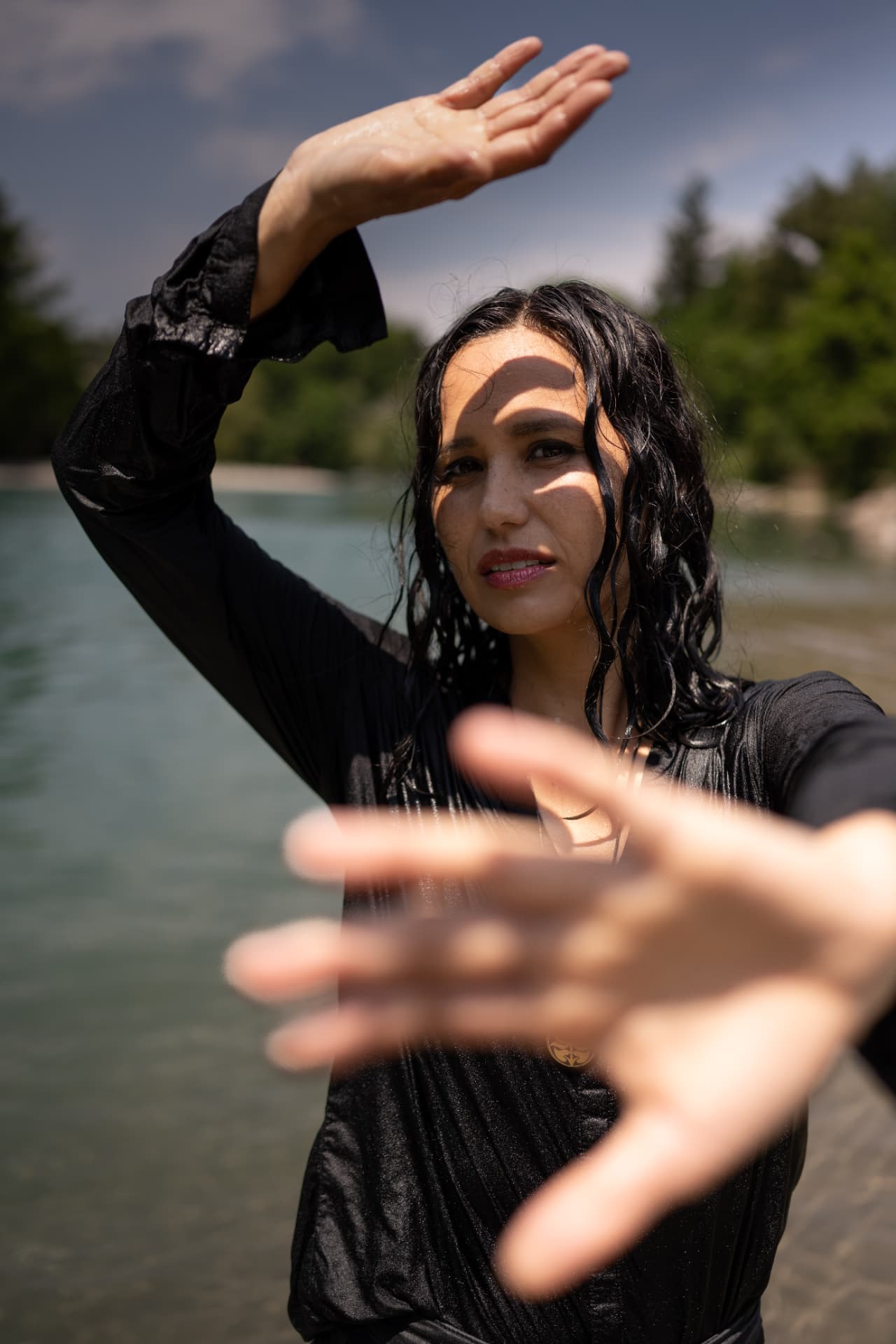 Meira Loom im Fluss mit nassen Haaren, eine Hand vor der Kamera