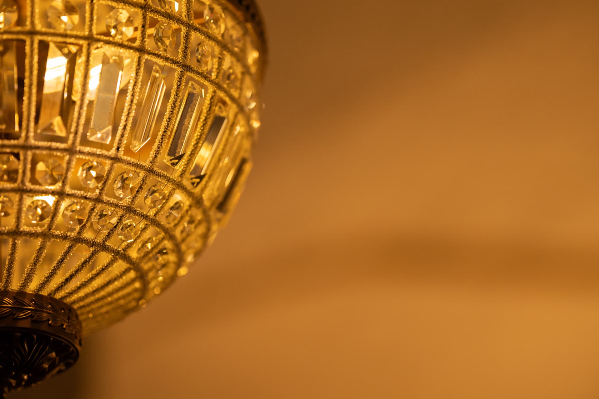 Warmly lit crystal chandelier against a softly blurred golden background