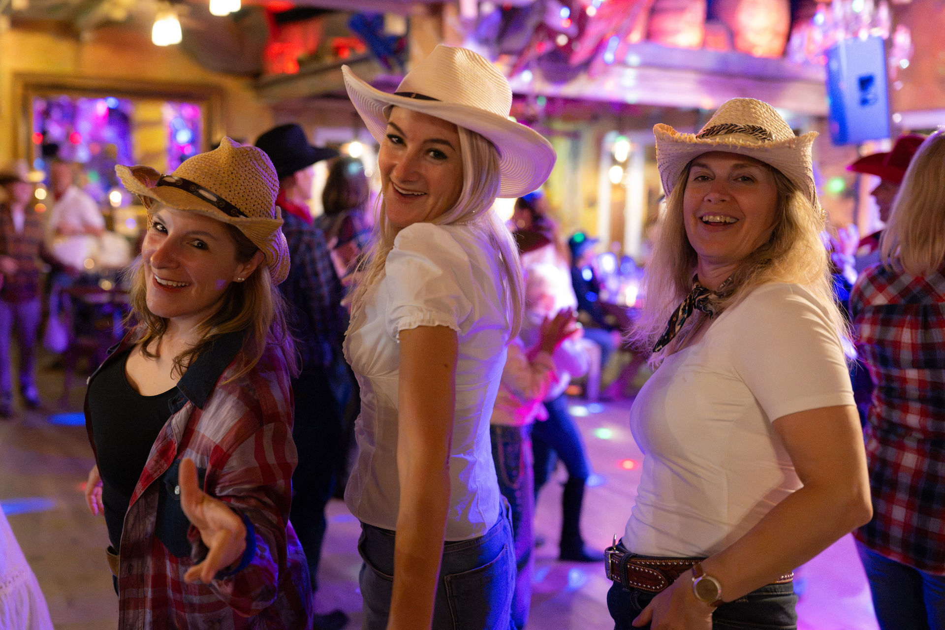 Drei Frauen tanzen in Cowboy-Outfits