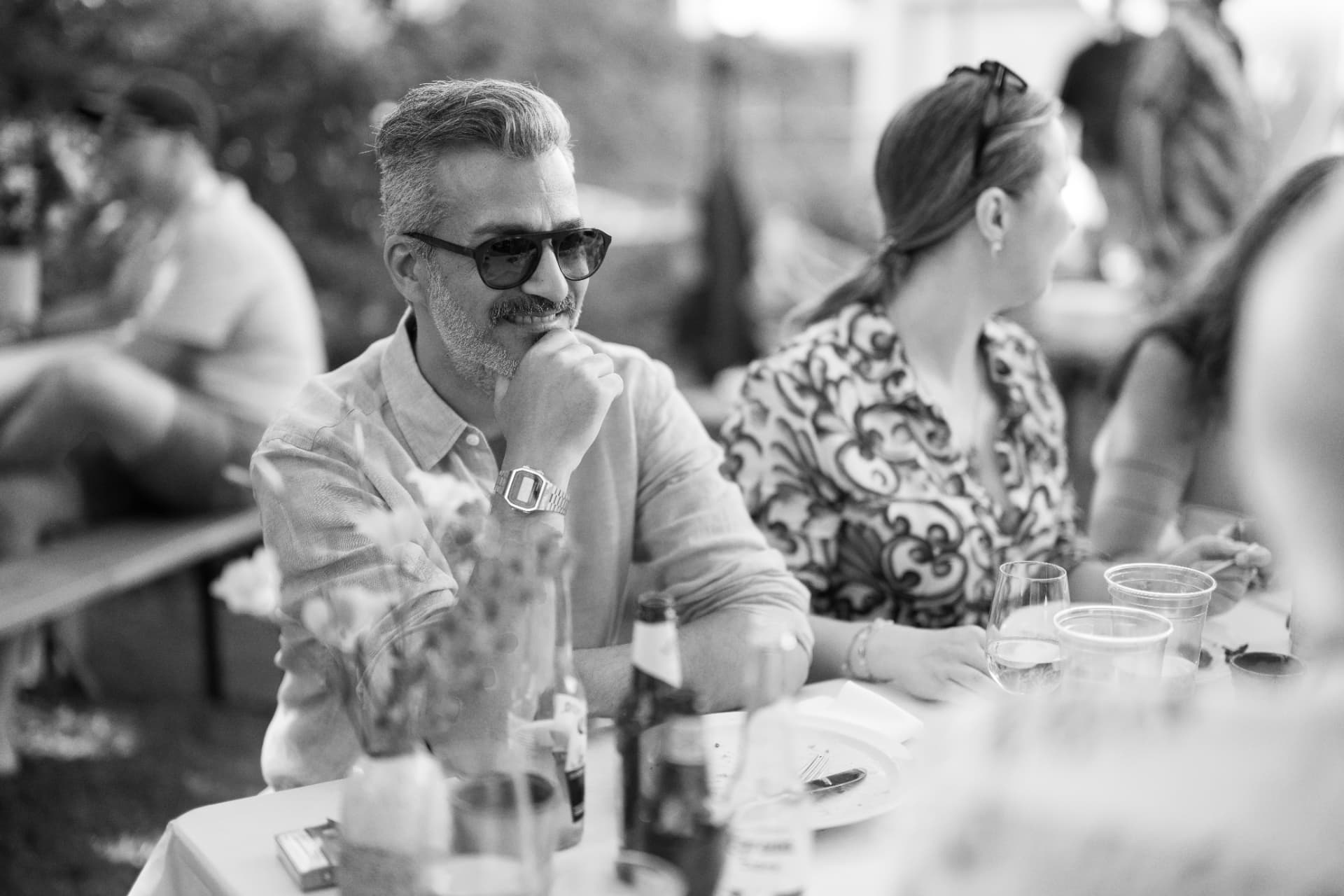 Gast mit Sonnenbrille sitzt am Tisch und lächelt