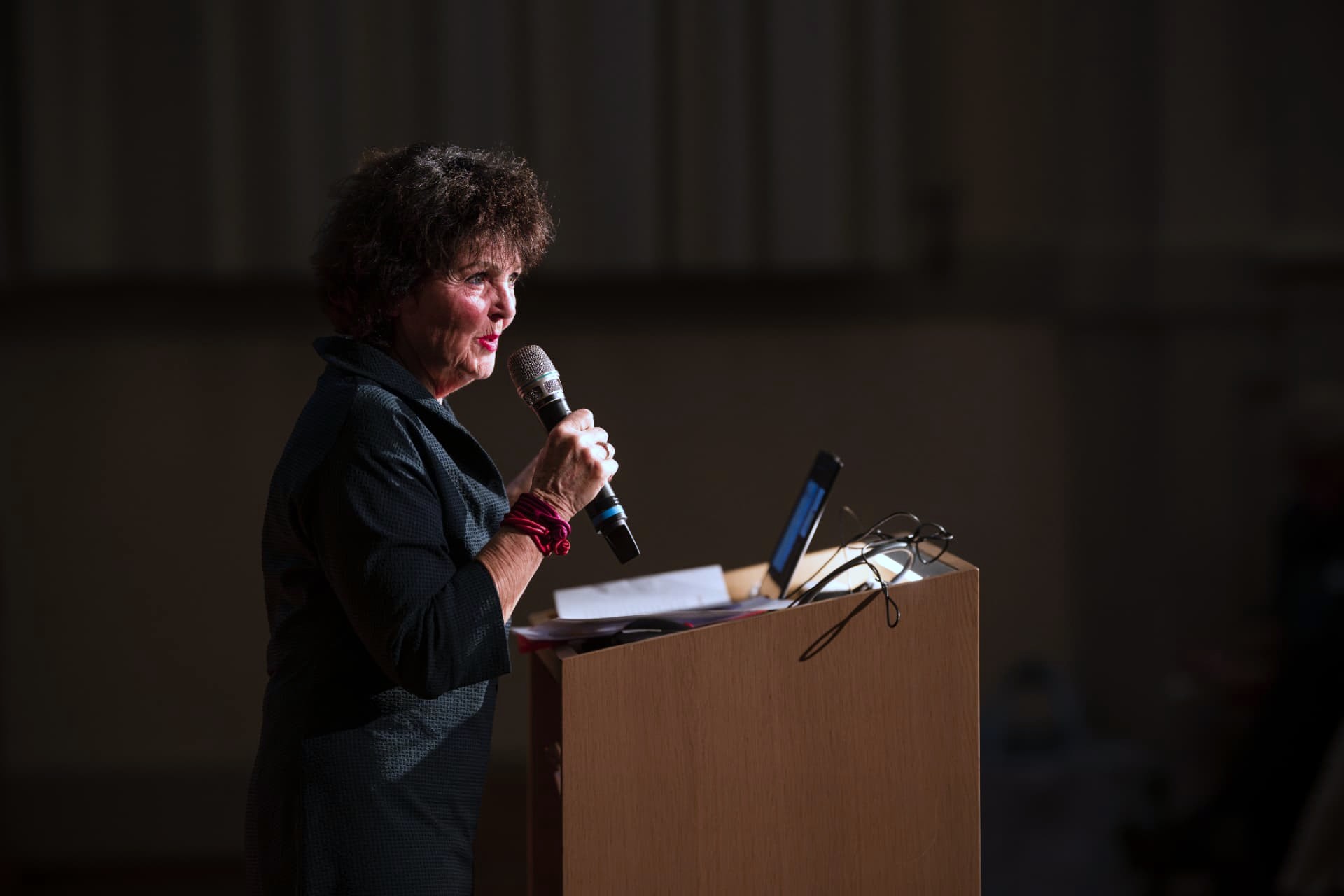 Woman speaking into a microphone at a wooden lectern