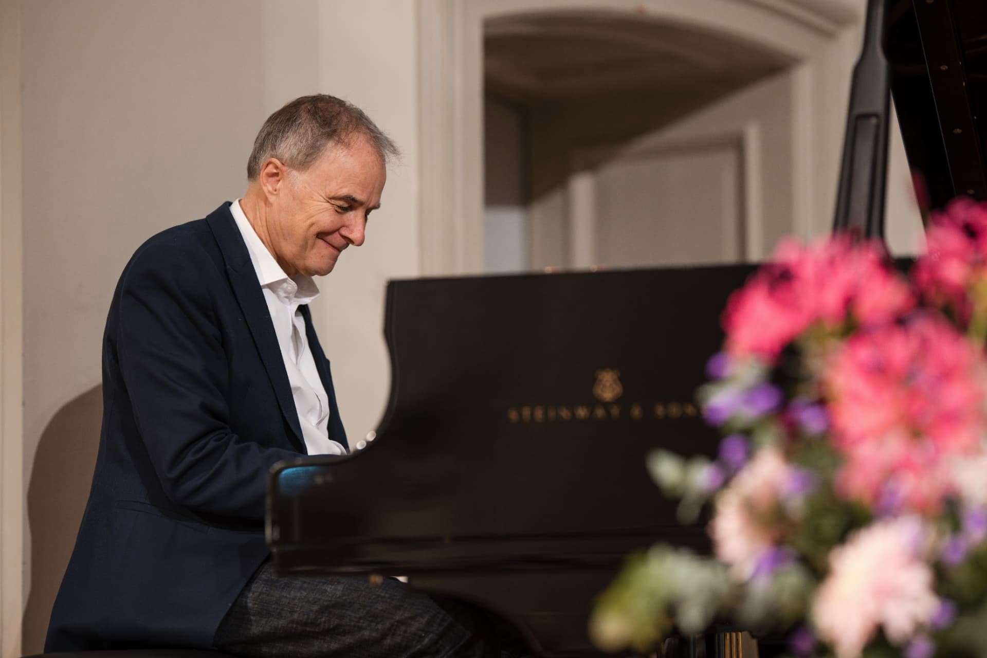 Man in a suit smiling as he plays the piano