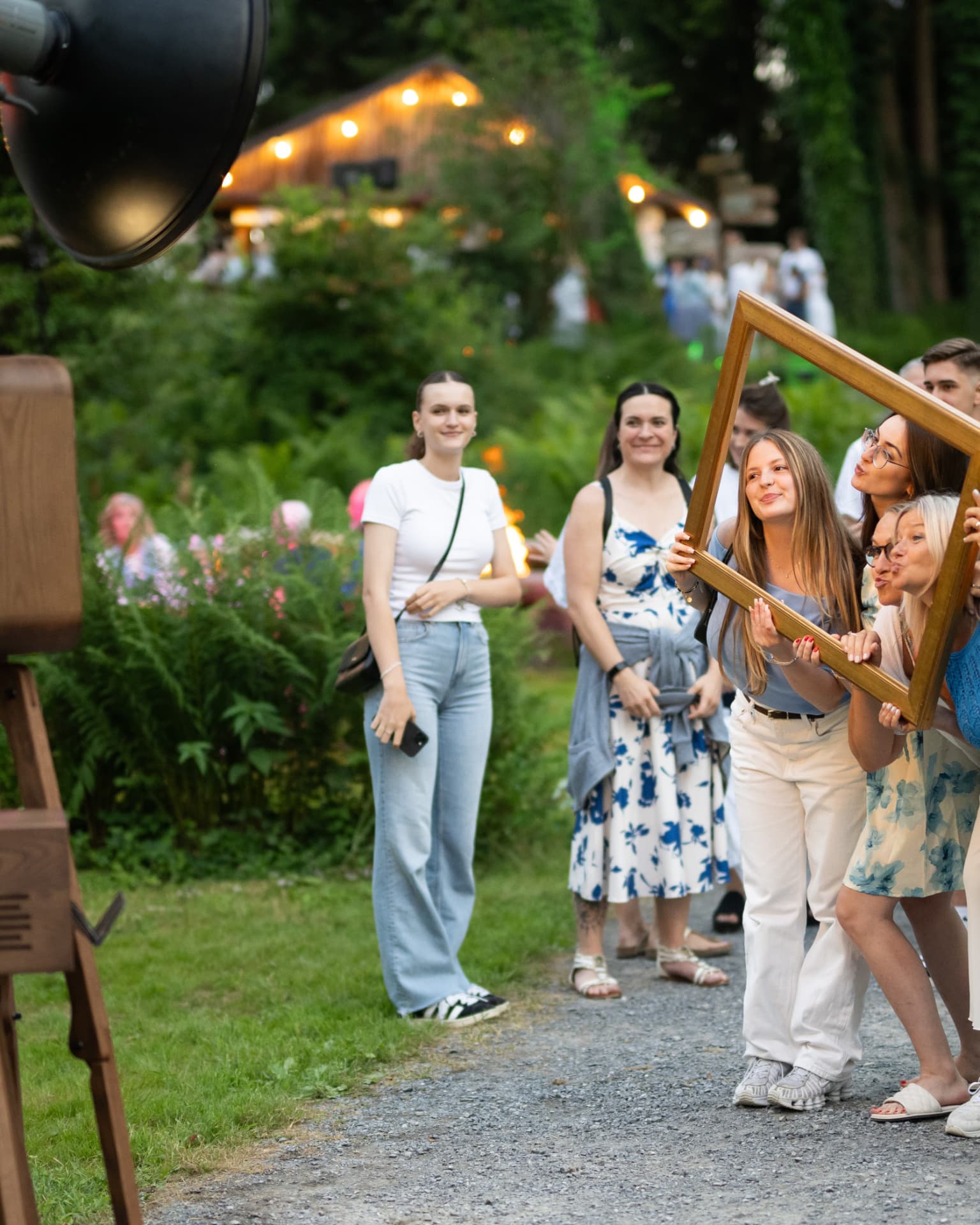 Guests posing with picture frames at a photo booth during an outdoor summer party