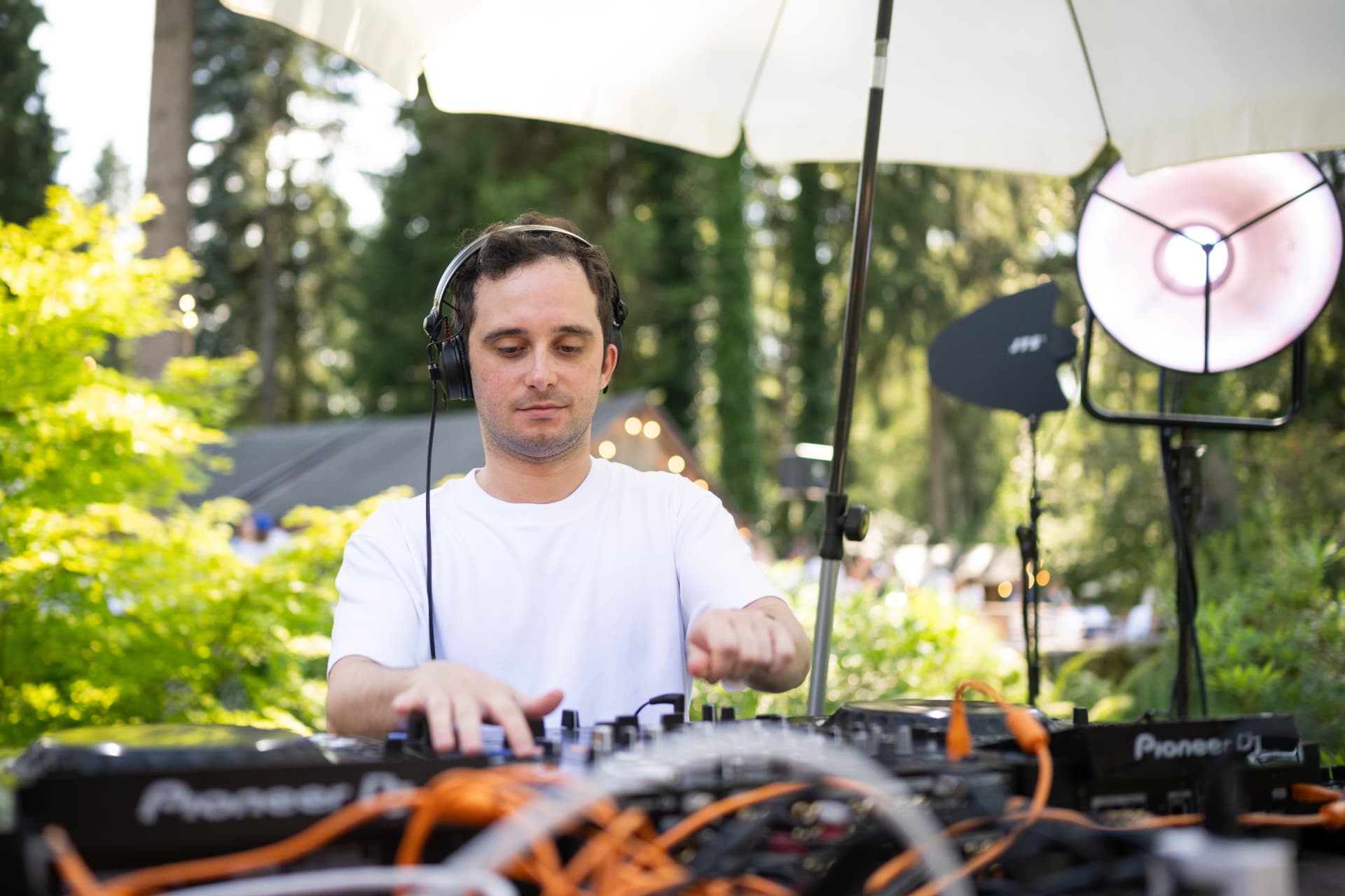 DJ mit Kopfhörern am Pult unter dem Sonnenschirm