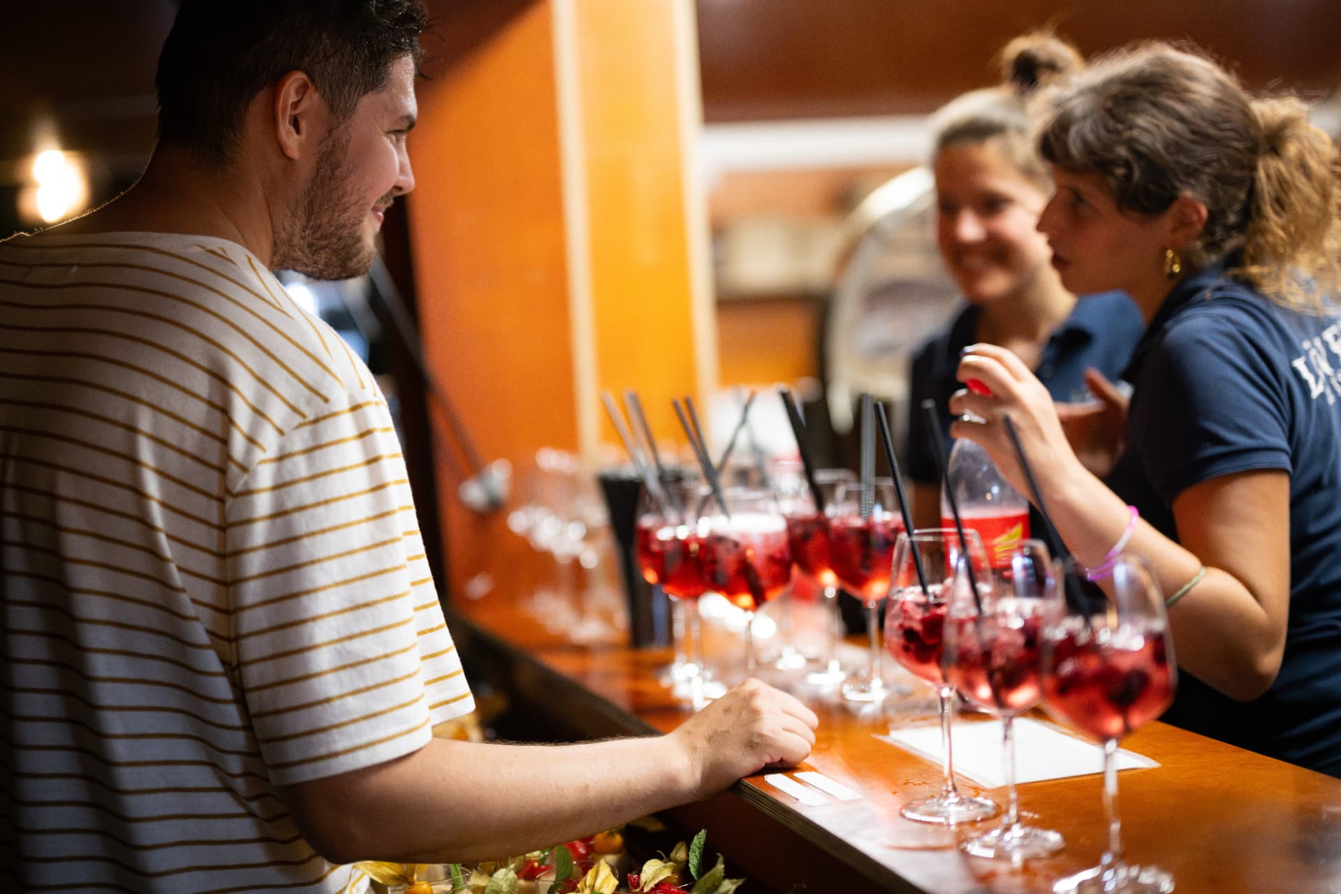 Lachende Gäste im Gespräch an der Bar beim Sommerfest