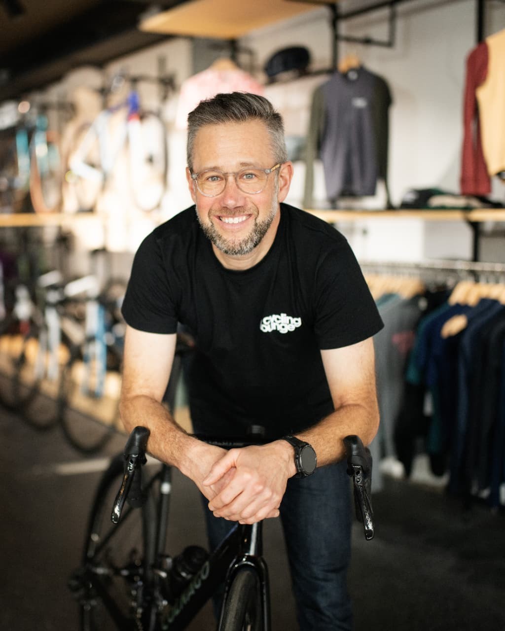 Porträt eines lächelnden Mannes mit seinem Rennrad im Fahrradgeschäft