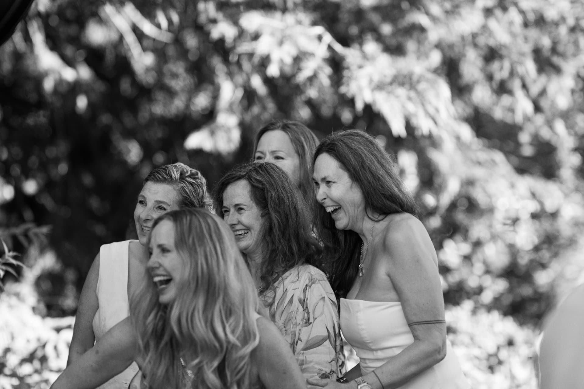 Fünf Frauen lachen zusammen im Grünen