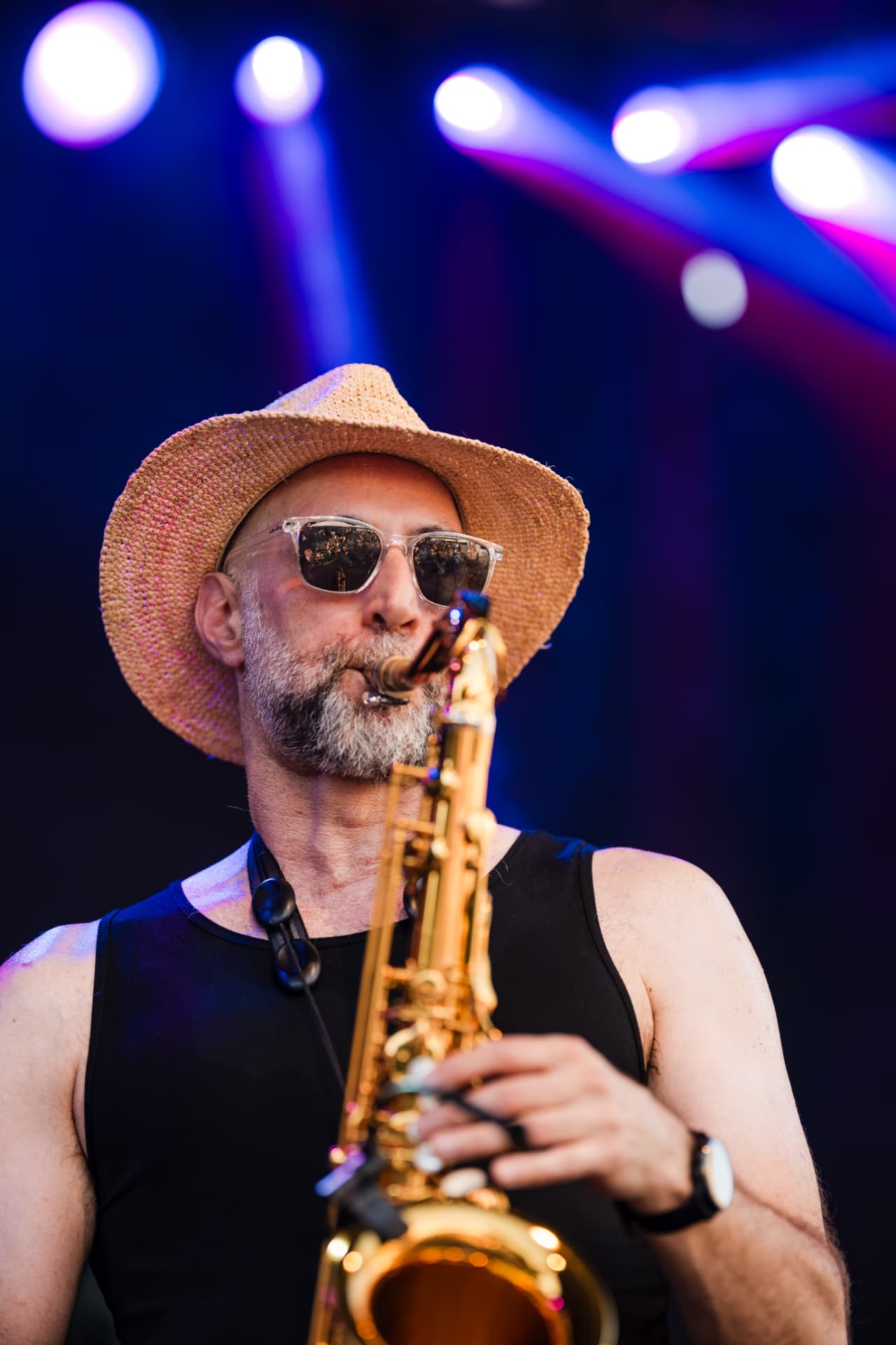 Saxophonist mit Strohhut vor lila Bühnenlicht