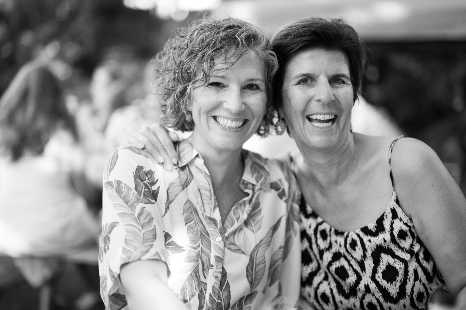 Zwei Frauen umarmen sich und lachen im Garten