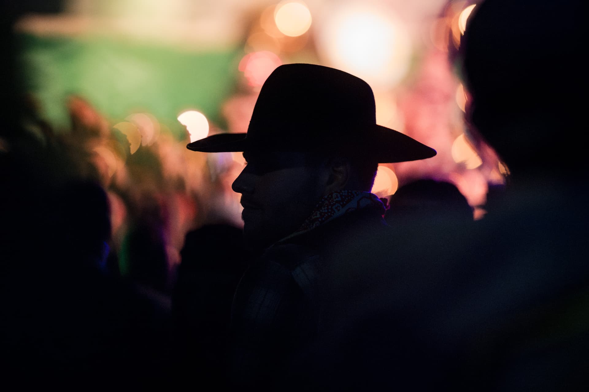 Silhouette mit Hut vor bunten Lichtern der Nachtfeier