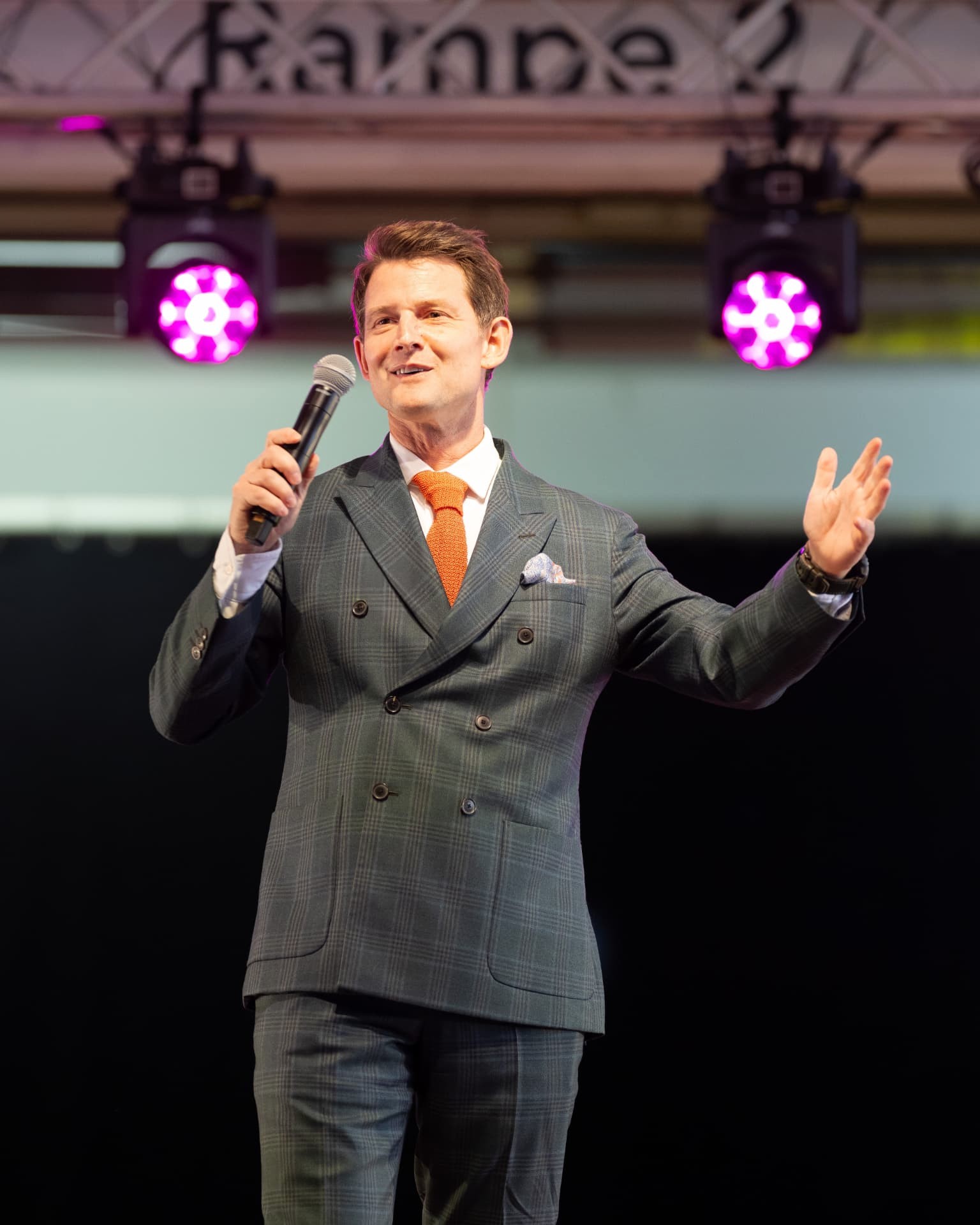 Speaker with a microphone on stage in magenta lighting