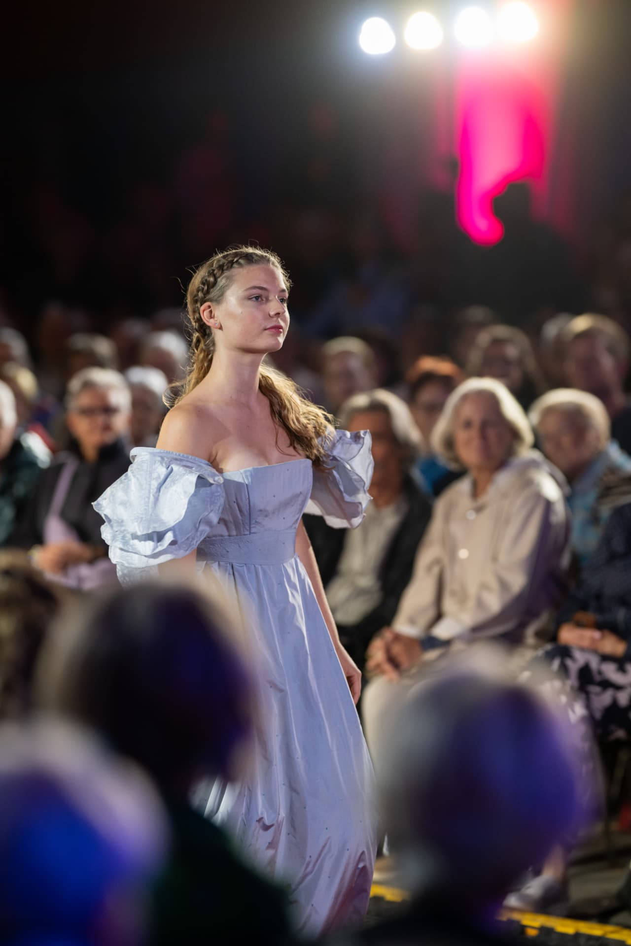 Model in hellem Kleid beim Modenschau-Auftritt am Abend