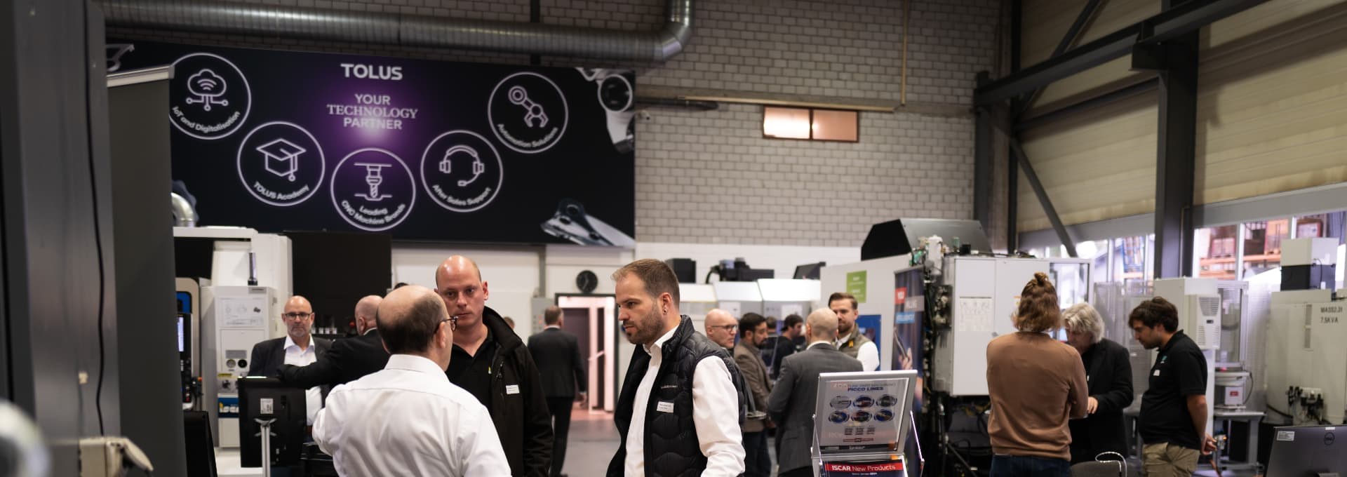 Ausstellungshalle in der Totalen: Besucher in kleinen Gruppen zwischen den ausgestellten Maschinen
