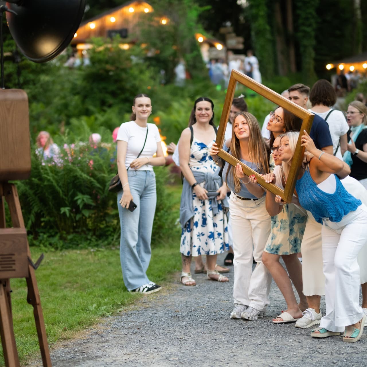 Photo booth at a summer party: guests posing with picture frames in front of the backdrop