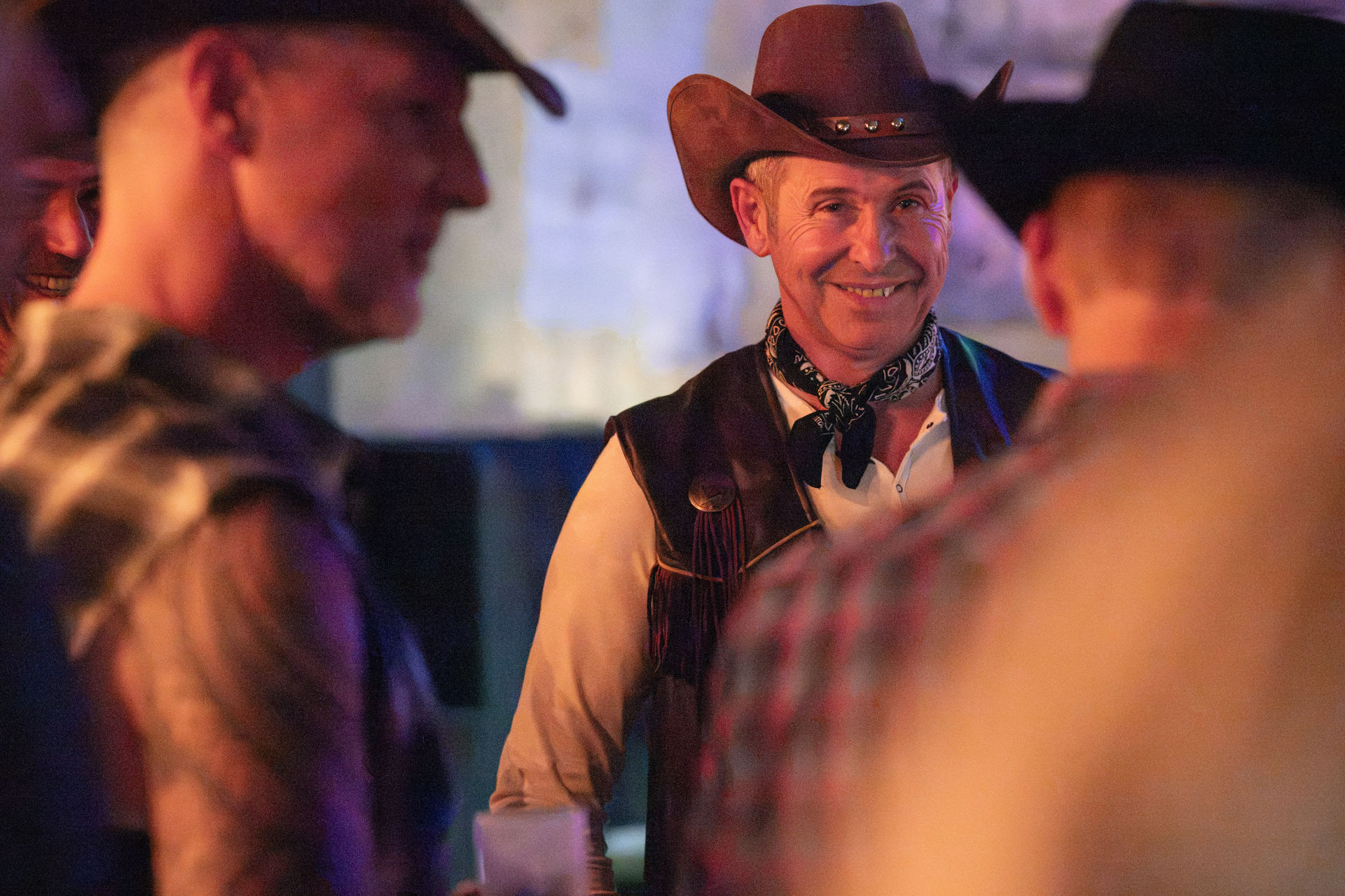 Gast mit Cowboyhut lacht im Licht der Feier